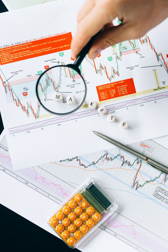 Offerings Magnifying glass focusing on market data and charts indicating financial analysis concept.