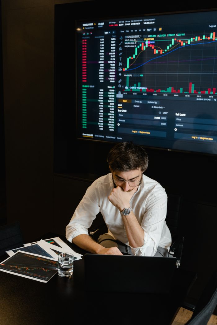 Offerings Adult man analyzing cryptocurrency data on a computer screen in an office setting.